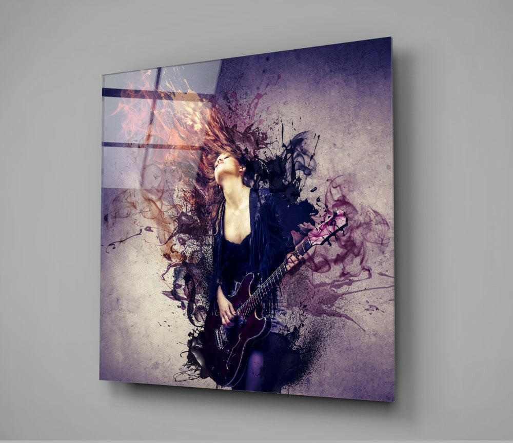 Angled view of glass wall art depicting a woman with long hair holding a guitar, featuring purple and orange watercolor effects with dark horizontal lines across the surface.