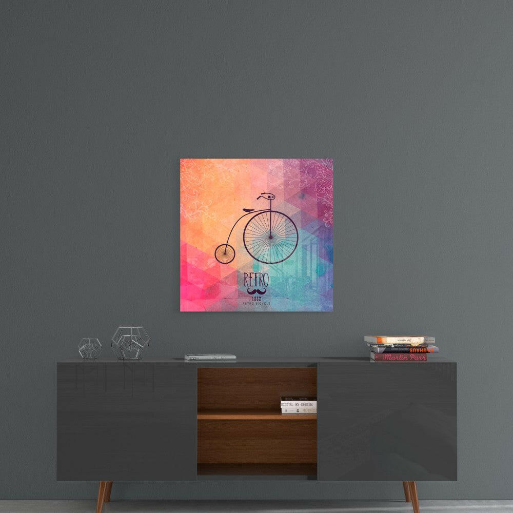 Retro bicycle glass wall art displayed above a mid-century modern sideboard, showing colorful gradient background transitioning from orange to pink to purple to blue.