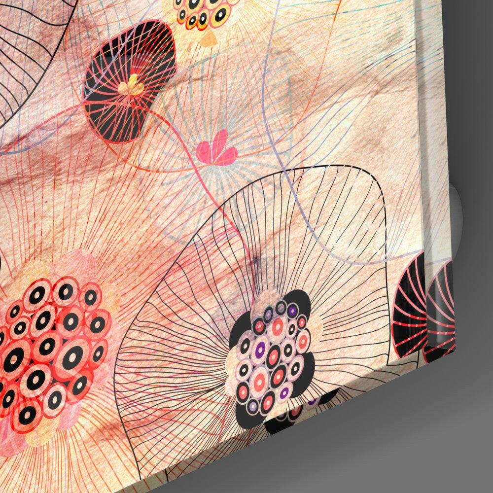 Close-up angled view of glass art showing abstract red and black flowers with radiating line patterns and circular eye-like details on cream background.
