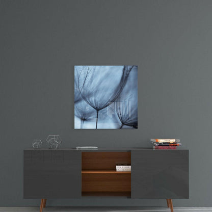Square glass wall art with blue-toned dandelion seed heads displayed above a mid-century modern credenza.