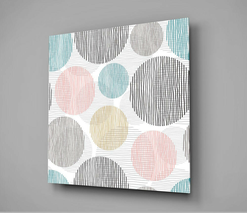 Modern glass wall art featuring overlapping circles in black, teal, pink, and beige with linear hatching patterns on white background, displayed at an angle.
