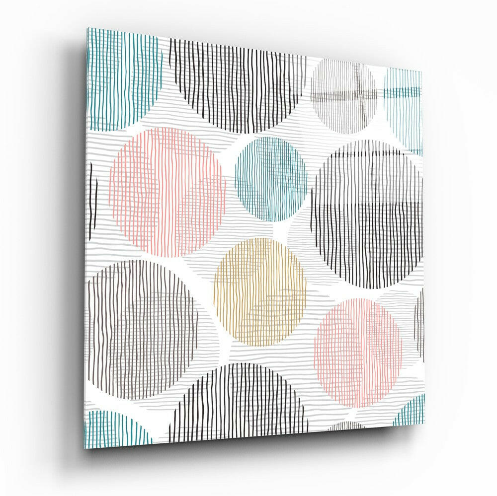 Angled view of glass wall art with overlapping circles in teal, black, coral, and tan filled with linear patterns on white background.