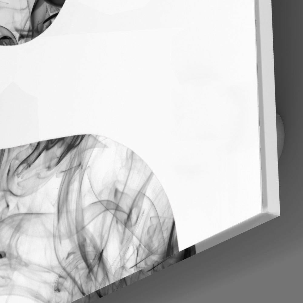 Close-up angled view of white glass panel with black smoke swirl patterns, mounted against gray wall.