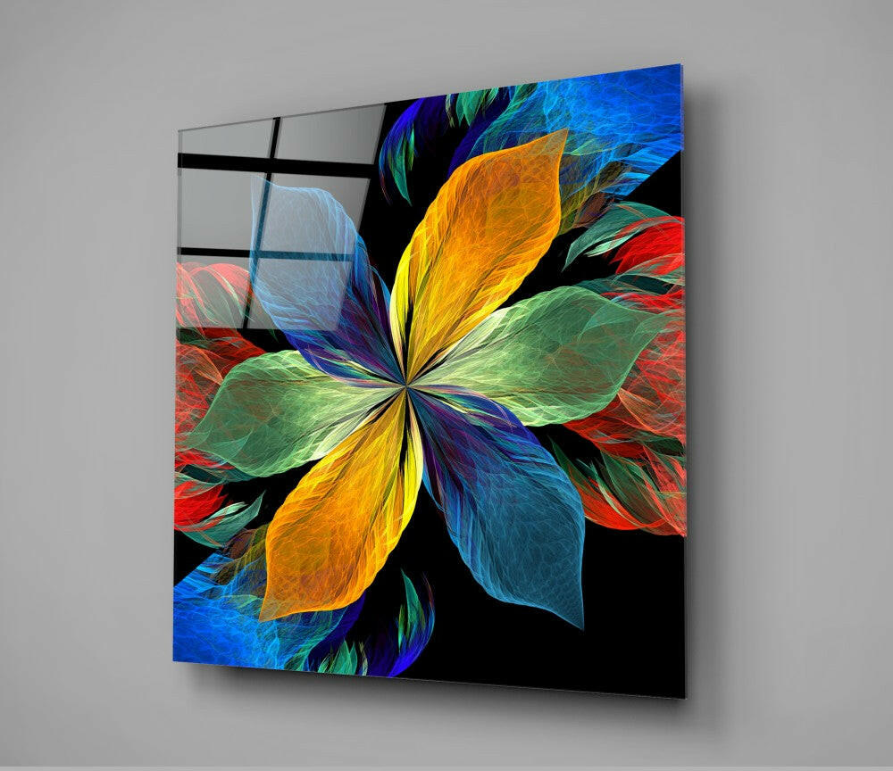 Colorful abstract flower glass wall art with vibrant yellow, blue, red, and green petals on black background, displayed at an angle against gray wall.