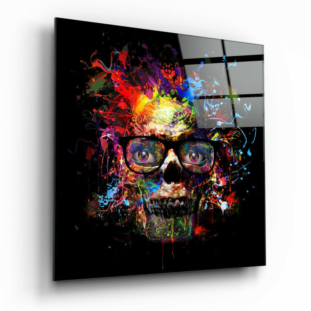 Colorful skull with glasses displayed on black glass panel, viewed at an angle showing vibrant paint splatter effects in reds, blues, yellows, and purples against dark background.