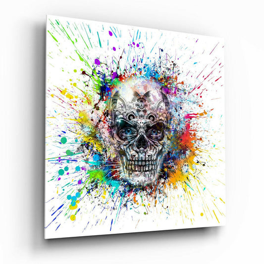 Angled perspective of glass wall art displaying an ornate mechanical skull surrounded by radiating multicolored paint splatters on white background.