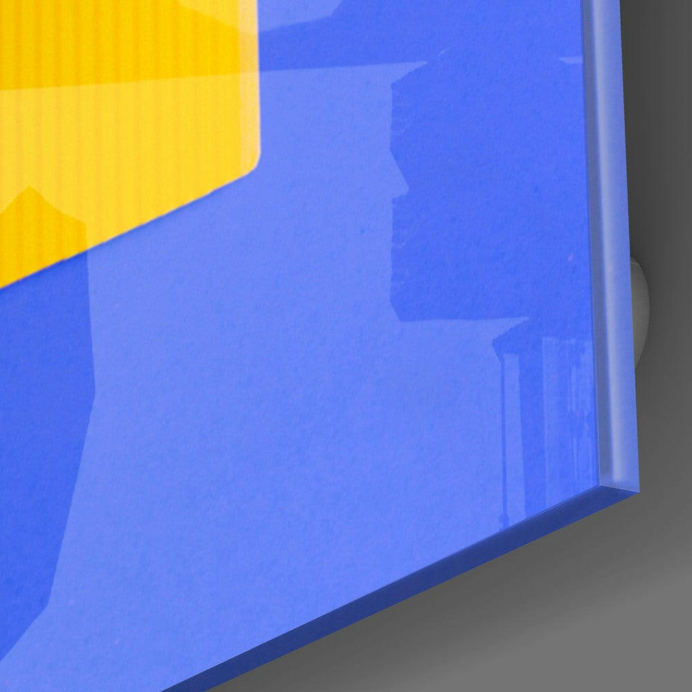 Close-up angled view of blue and yellow glass wall art with glossy surface and beveled edge against gray background.