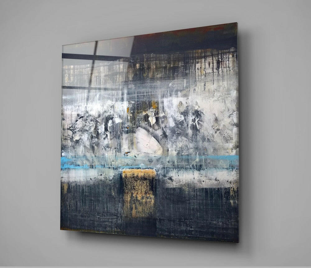Abstract glass wall art with layered composition featuring dark navy and white tones, gold accents, and blue stripe, mounted at angle on gray wall.