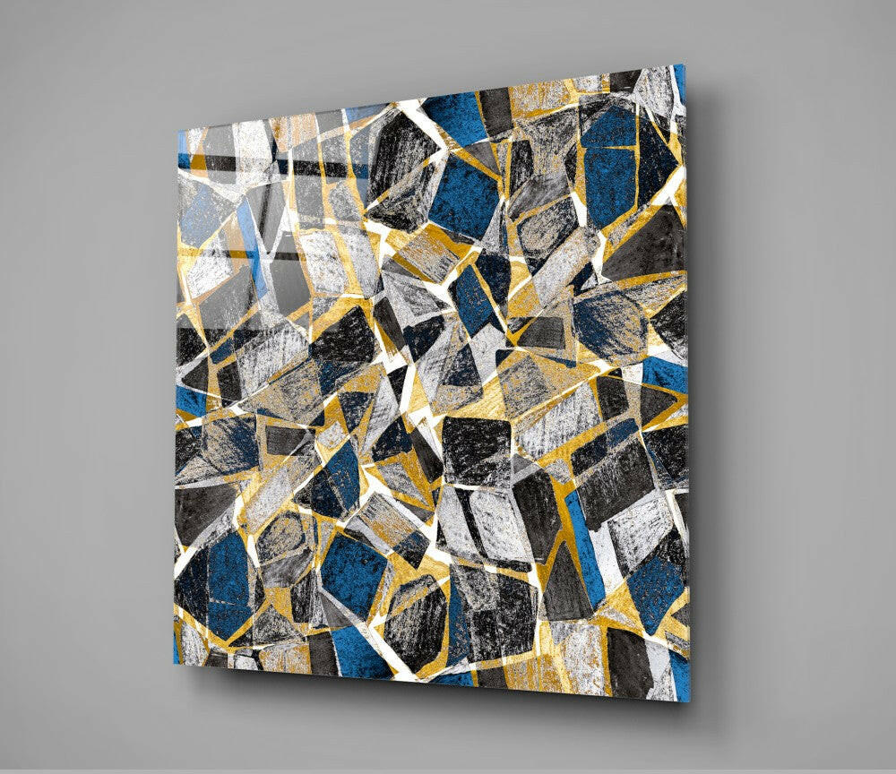 Square glass wall art with geometric honeycomb pattern in blue, gold, black, white, and gray segments displayed at an angle.
