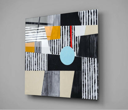 Abstract glass wall art featuring geometric shapes in black, white, gray, yellow, cream, and a centered light blue oval against a neutral background.