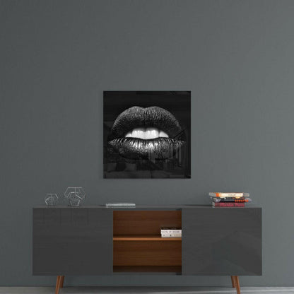Black and white glass wall art featuring glossy lips displayed above a mid-century modern credenza in a styled interior setting.
