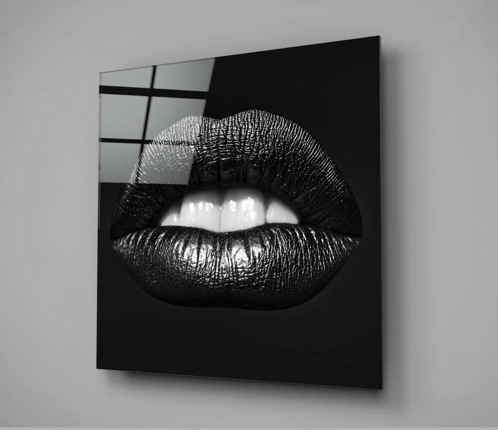 Black and white close-up of glossy lips on dark glass panel mounted on gray wall, window reflection visible upper left.