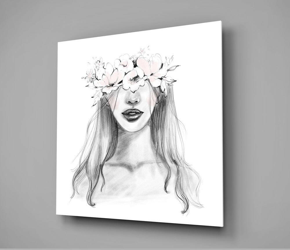 Glass wall art displaying a pencil sketch of a woman's face with long wavy hair and a floral crown, mounted on gray wall.
