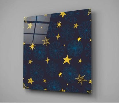 Angled front view of square glass wall art featuring dark navy background with gold stars and teal snowflakes, mounted on gray wall.