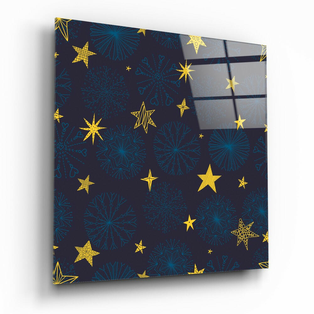 Angled view of glass wall art panel with dark navy background featuring gold stars and blue snowflakes pattern.
