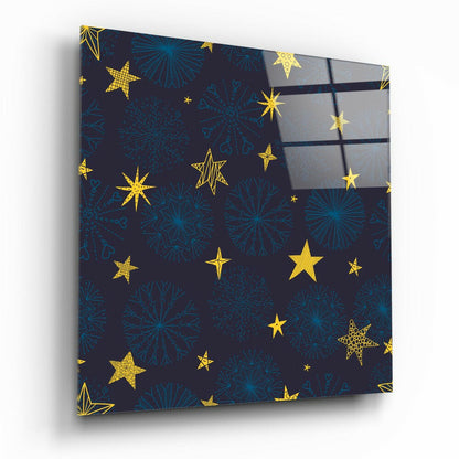 Angled view of glass wall art panel with dark navy background featuring gold stars and blue snowflakes pattern.