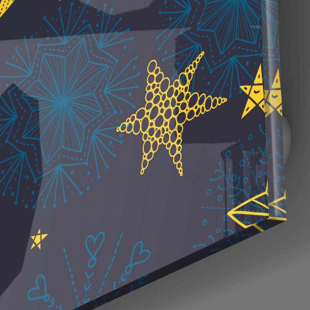 Angled close-up of dark glass panel with blue snowflake patterns and yellow geometric reindeer and star designs.