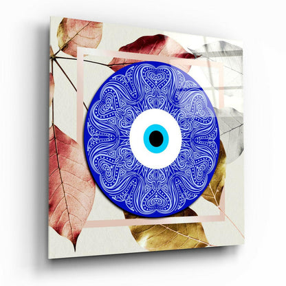 Blue ornamental evil eye glass wall art with cyan iris centered on cream background surrounded by autumn leaves in red and gold tones.