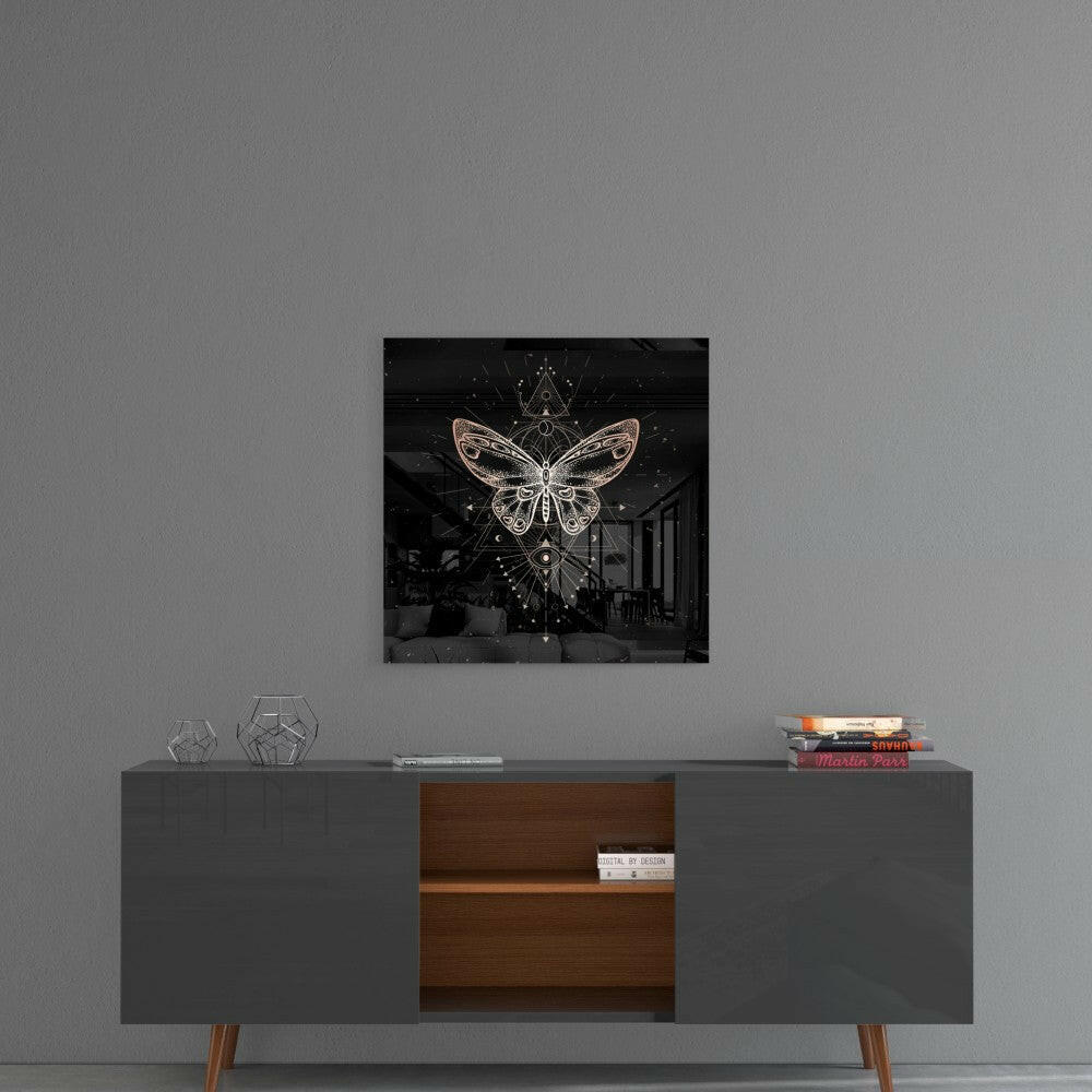 Square glass wall art with golden glowing butterfly design on black background, displayed above mid-century modern console table.