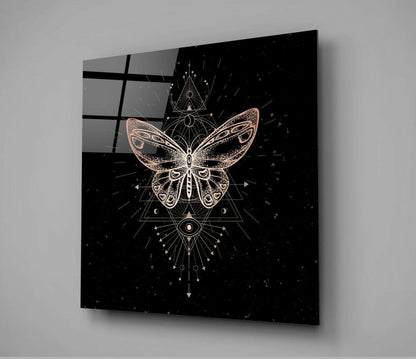 Angled view of square glass wall art displaying a copper and white butterfly with geometric sacred geometry symbols on black background.