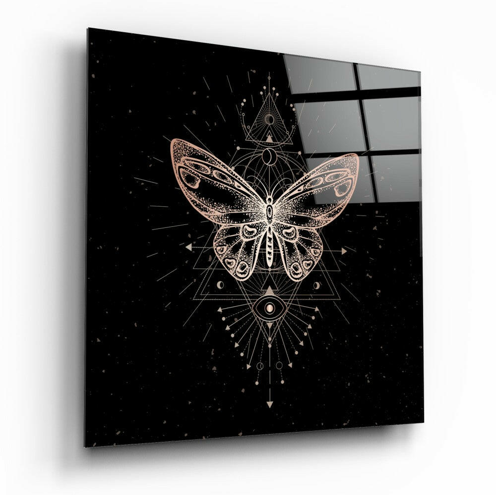 Square glass panel displaying a gold geometric butterfly design with sacred symbols on black background, angled perspective view.