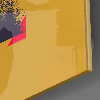 Close-up angled view of yellow glass wall art with pink and dark blue geometric shapes and scattered particle effect detail.