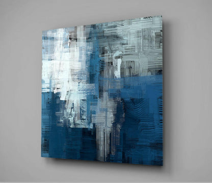 Blue Touch Glass Wall Art displayed at an angle against a gray wall, showing white, light blue, and dark blue brushstroke patterns.