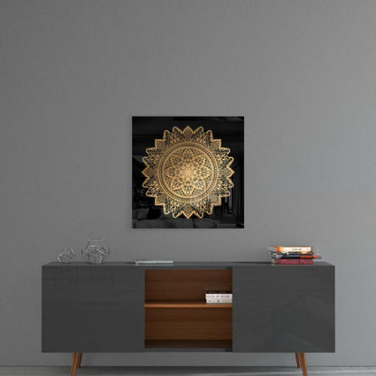 Gold ornamental mandala on black glass mounted above mid-century modern credenza in minimalist interior setting.