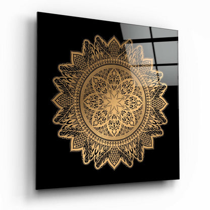 Gold ornate mandala design on black glass panel displayed at an angle, showing reflections on the surface.