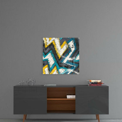 Abstract geometric glass art with blue, yellow, white, and gray chevron pattern hanging above mid-century modern credenza.
