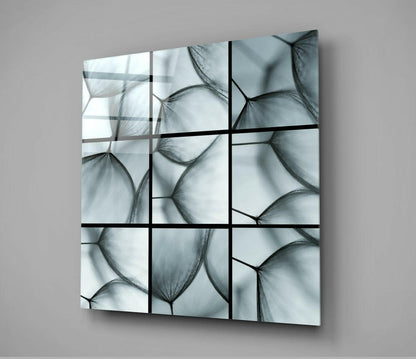 Nine-panel glass wall art featuring translucent dandelion seed heads in grayscale, mounted at an angle against a neutral background.