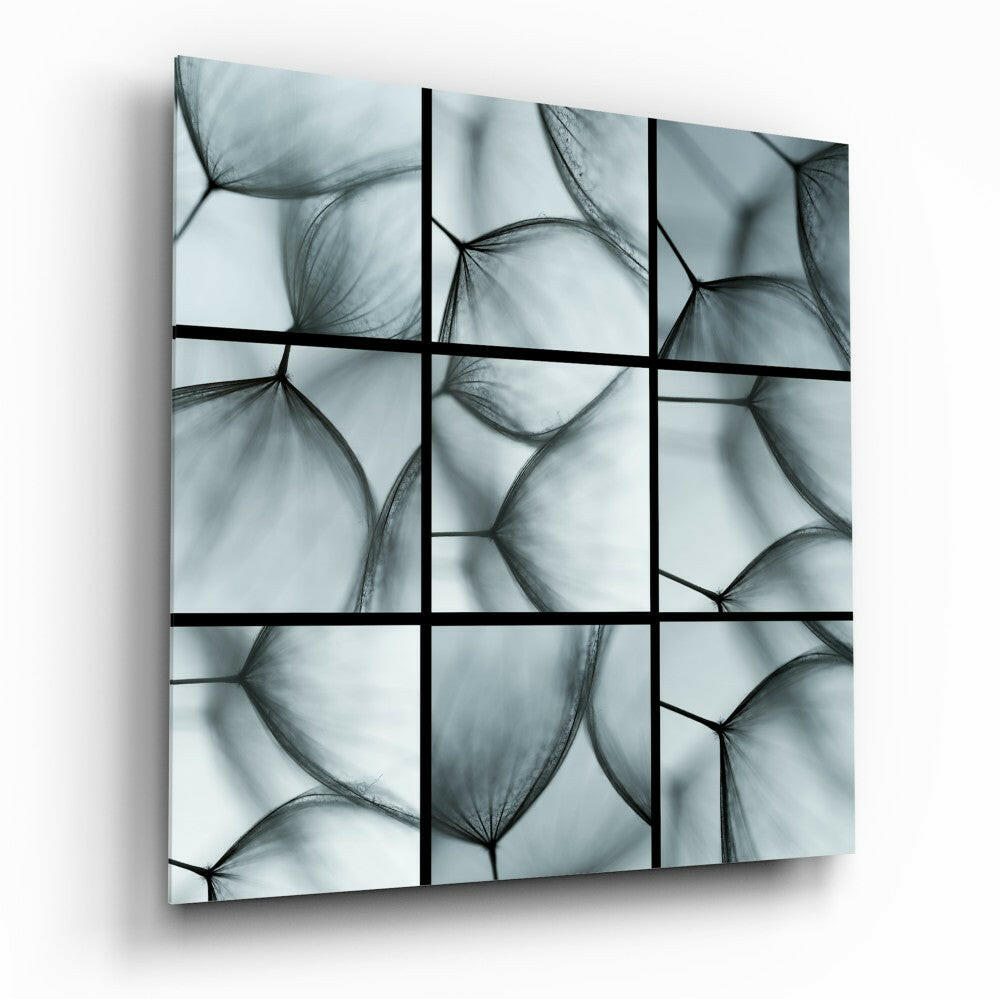 A 3x3 grid glass wall art panel featuring translucent dandelion seed heads in grayscale tones divided by black lines.