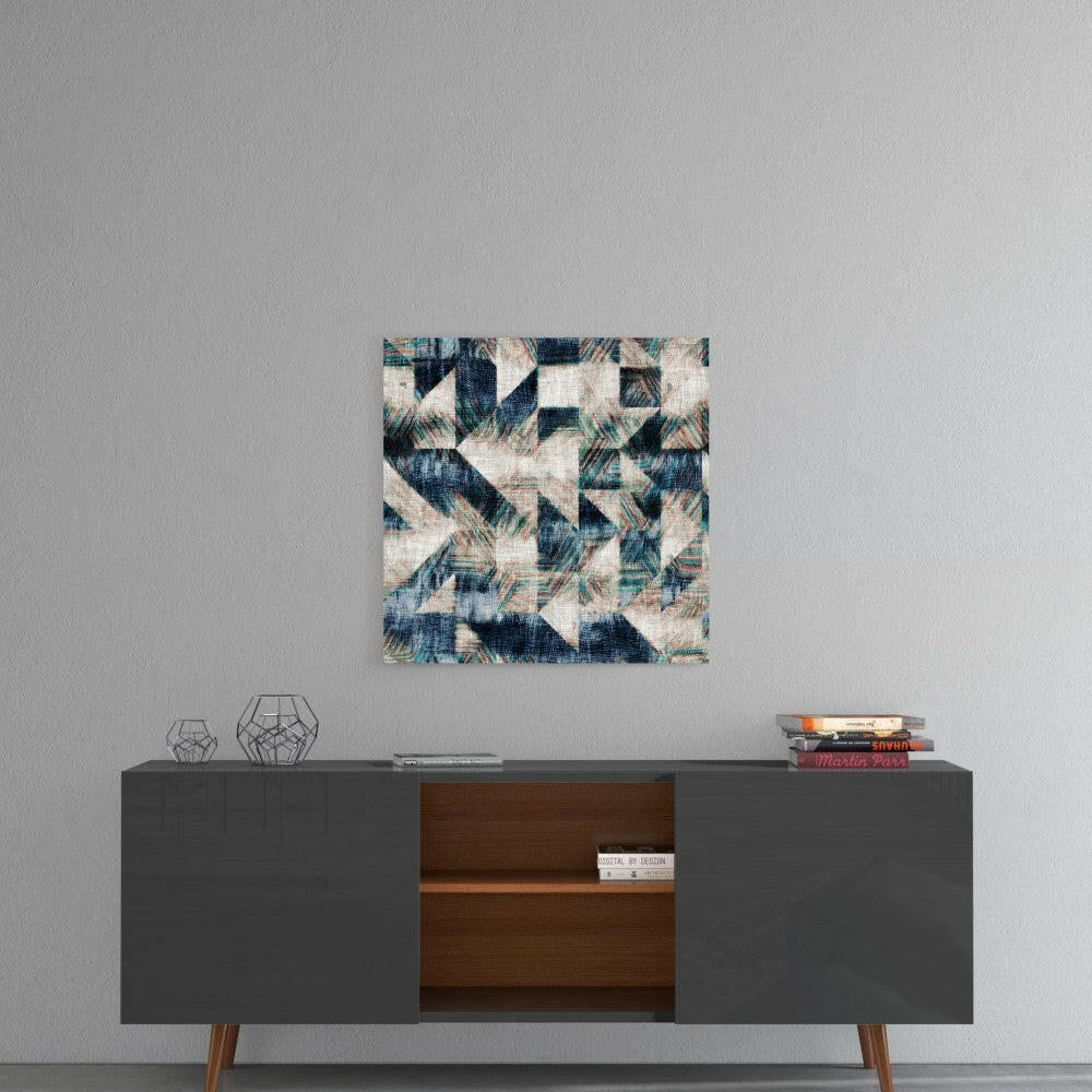 Abstract geometric glass wall art with navy, teal, and cream triangular pattern displayed above mid-century modern sideboard.
