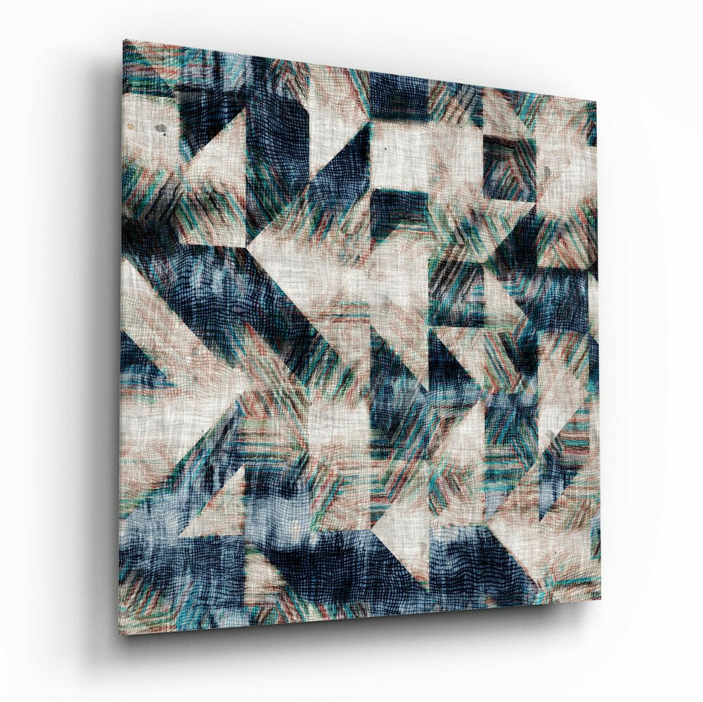 Angled view of geometric glass wall art featuring navy, teal, cream, and rust patterned triangles on textured linen surface.