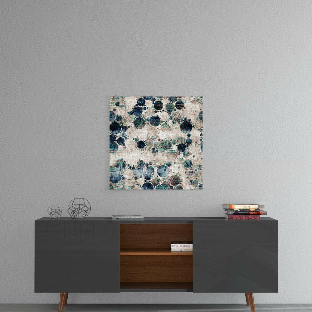 Square glass wall art with blue and teal circular microscope pattern on cream background, hung above mid-century modern console table.
