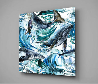 Glass wall art featuring multiple whales among swirling blue and teal waves with white splashes, mounted on gray wall.
