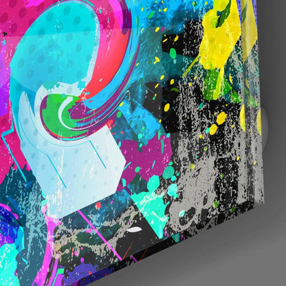 Close-up angled view of vibrant abstract glass wall art with neon pink, cyan, yellow, and green splattered paint effects on black textured surface.