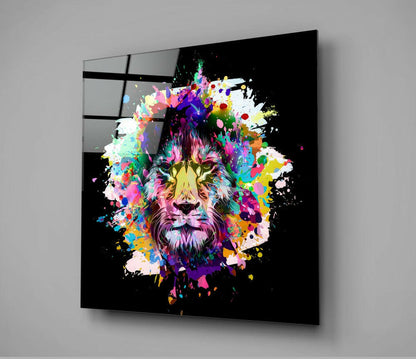 Angled view of black glass wall art displaying a colorful, paint-splattered lion head with vibrant rainbow hues against dark background.