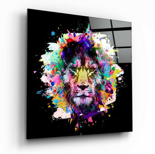 A square glass panel displaying a colorful, paint-splatter lion portrait on black background, shown at an angle against a white wall.