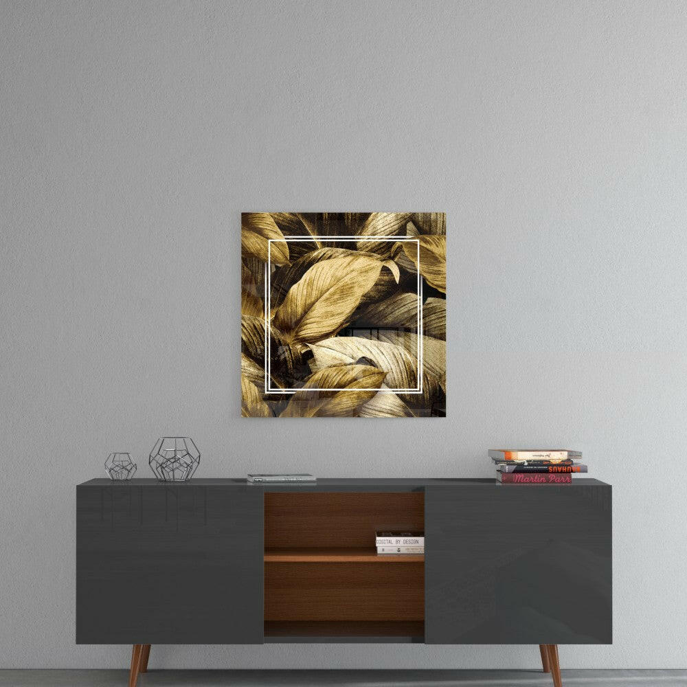 Gold leaf glass wall art with white border frame displayed above mid-century modern credenza with geometric decor.