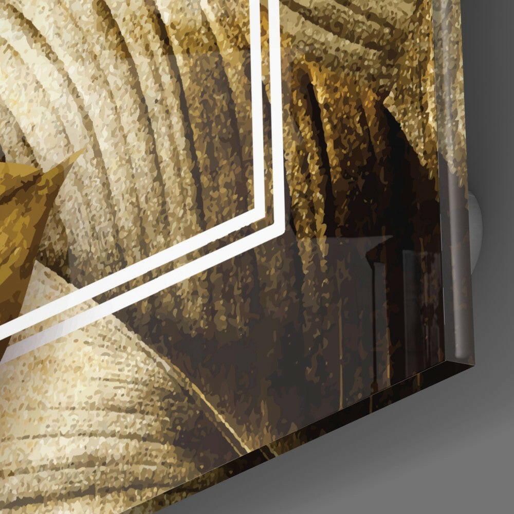 Close-up angled view of gold leaf glass wall art with white trim edge against gray background, showing textured gold and cream layered design.