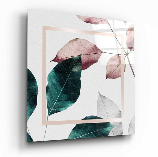 Angled view of glass wall art displaying pressed leaves in mauve, teal, and gray tones with a pale pink rectangular frame on white background.