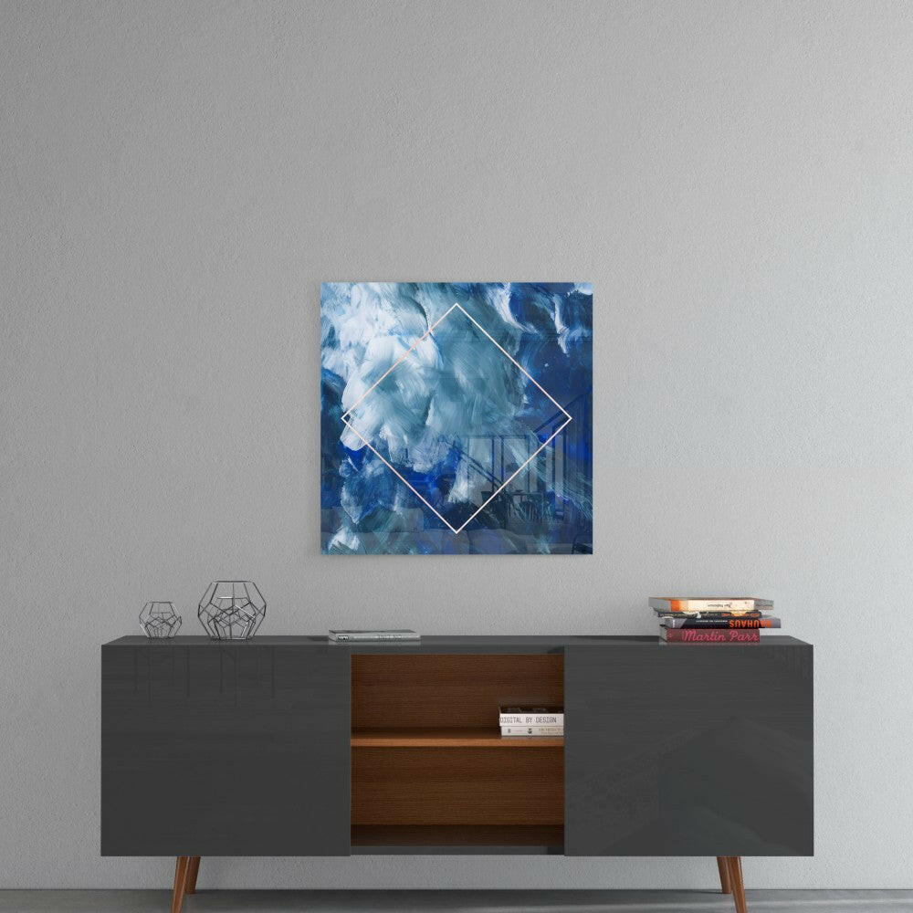 Blue and white abstract cloud glass art with white diamond outline displayed above modern credenza with geometric decor.