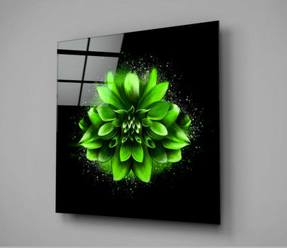Angled view of black glass wall art displaying a vibrant neon green flower with particle effects against dark background.