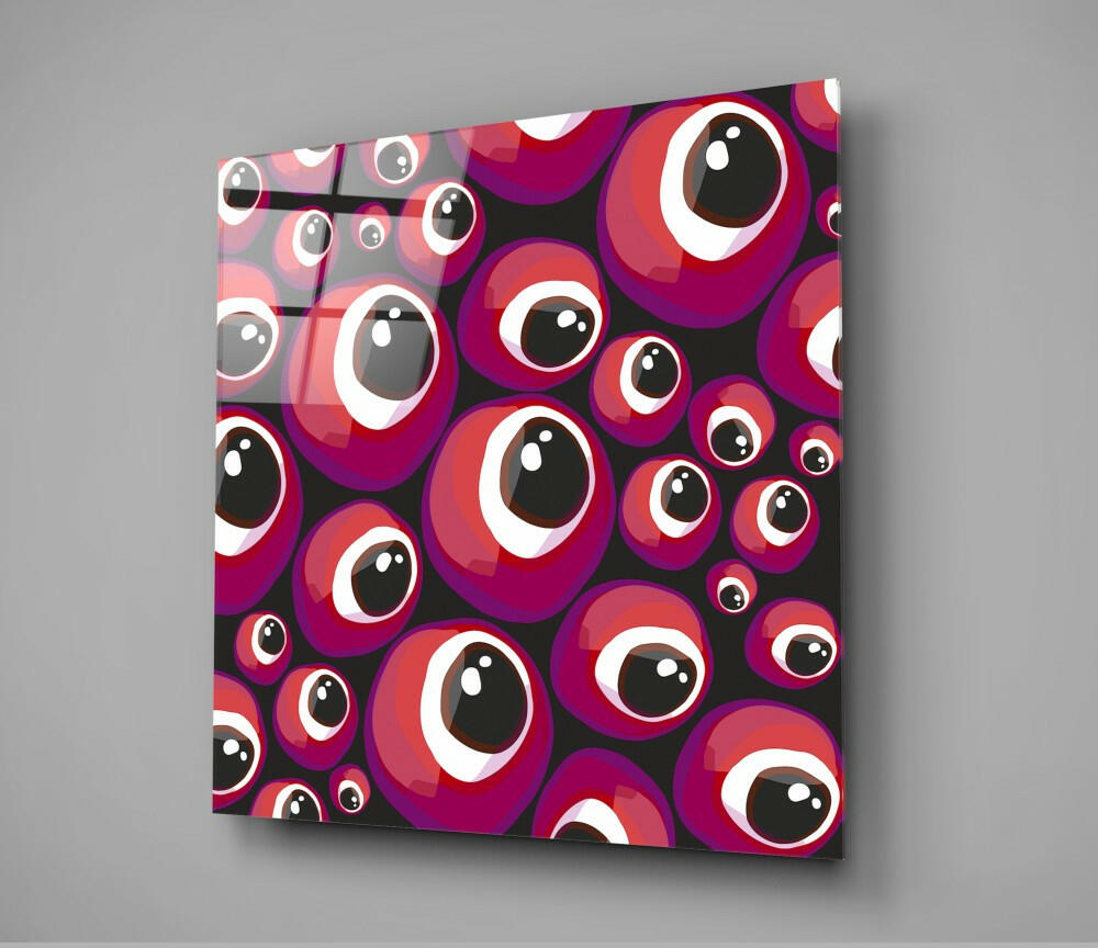 Angled front view of glass wall art panel displaying red and purple evil eye beads pattern on black background.