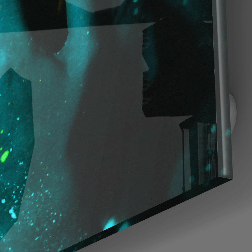 Close-up angled view of emerald green glass wall art with luminescent turquoise particles and silhouetted figure profile.