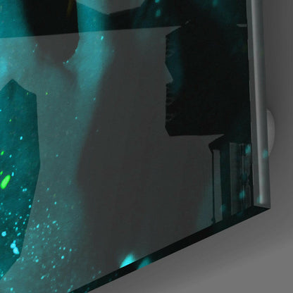 Close-up angled view of emerald green glass wall art with luminescent turquoise particles and silhouetted figure profile.