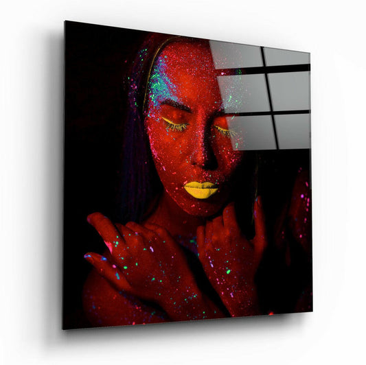 Glass wall art panel displaying a woman's face and shoulders covered in red glitter with yellow lips and colorful sparkles, mounted at an angle.