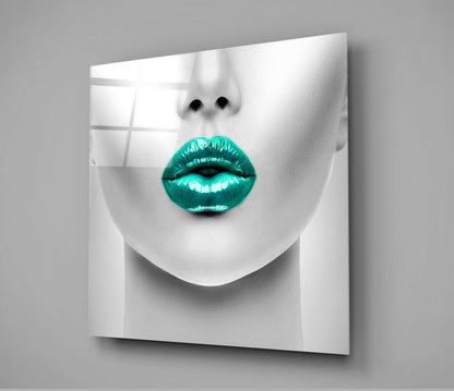 Close-up of glass wall art featuring a monochromatic face with bright turquoise metallic lips against gray background.