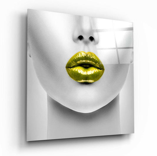 Close-up front view of a white sculptural face with bright gold metallic lips against a white gridded background, mounted as glass wall art.